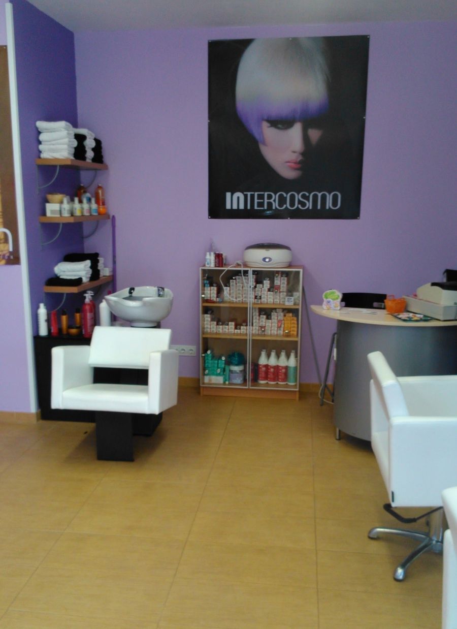 Entrada del salón con lavacabezas, estantería de productos y paredes lilas