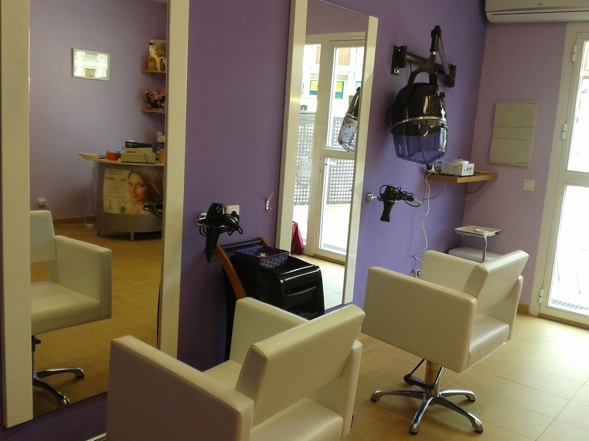 Puestos de peluquería con sillones claros, espejos y paredes lilas